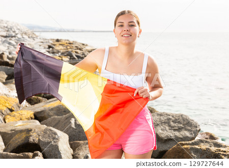 Young woman on coast posing with flag of Belgium 129727644
