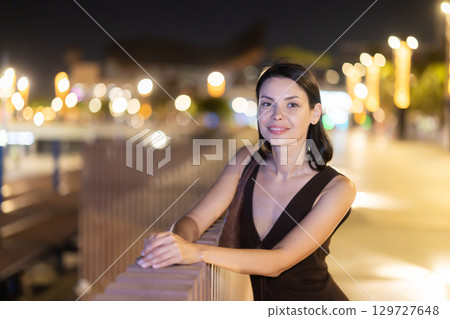 At night, smiling girl walks around old city district Barceloneta, in vicinage of Citadel Park 129727648