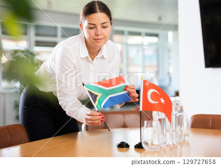 Female employee of the delegation sets flags of countries of Turkey and South Africa on the table before start of negotiations 129727658