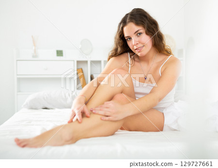 Carefree girl in lingerie sitting on bed after waking up Carefree girl in lingerie sitting on bed after waking up 129727661