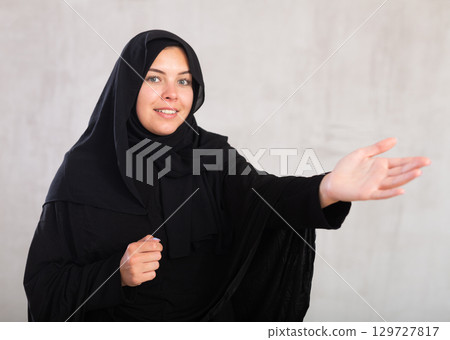 Young female in black hijab pointing at you - Portrait of young woman pointing her finger 129727817