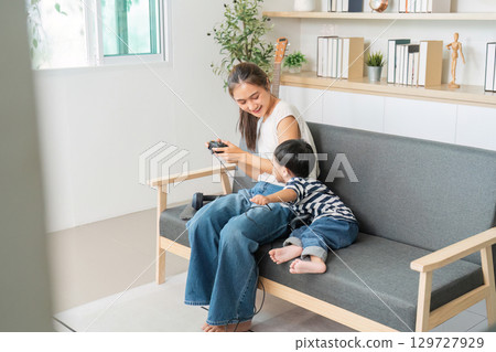 Family Fun. Mother and son enjoying video games on a comfortable sofa. Family Fun. Mother and son enjoying video games on a comfortable sofa. 129727929