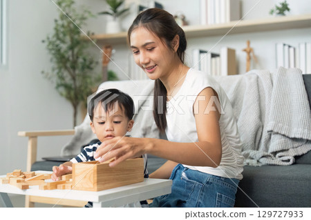 Interactive Learning. Mother and child playing with wooden blocks at home. 129727933