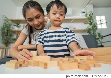 Learning Through Play. Mother and son engaged in building blocks activity. 129727942