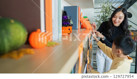 Halloween Celebration. A mother and son decorating for Halloween with pumpkins and crafts. 129727954