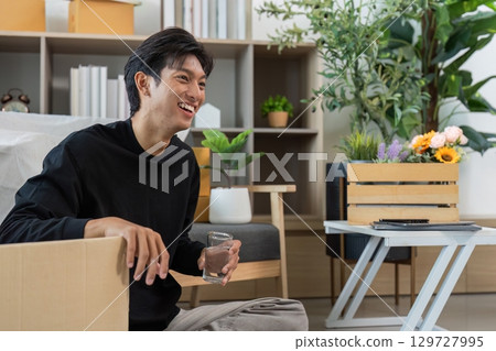 Young man enjoying a moment of relaxation at home with a glass of water 129727995