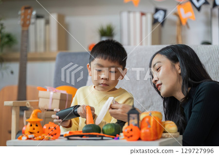 Halloween Crafts. A mother and son creating festive decorations together. Halloween Crafts. A mother and son creating festive decorations together. 129727996