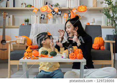 Halloween Playtime. Mother and son sharing spooky fun with decorations. 129728008
