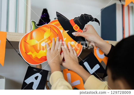 Halloween Decorations. A mother and son excitedly hanging Halloween-themed items together. Halloween Decorations. A mother and son excitedly hanging Halloween-themed items together. 129728009