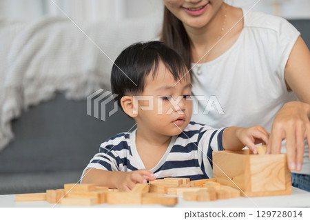 Mother and child building with wooden blocks at home Mother and child building with wooden blocks at home 129728014