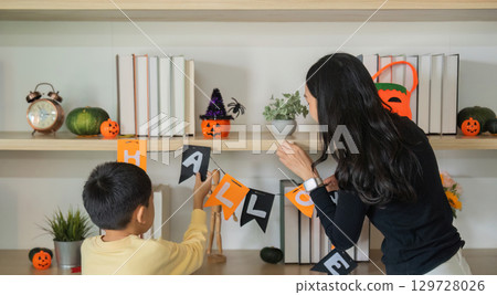 Halloween Decoration. A mother and son hanging Halloween banners together at home. Halloween Decoration. A mother and son hanging Halloween banners together at home. 129728026