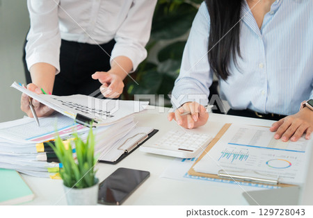Business Collaboration. Two professionals discussing project details with documents on the table. 129728043