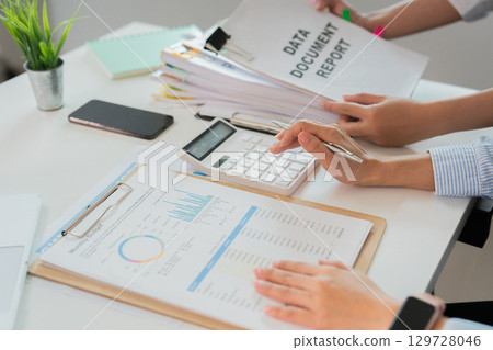 Data Analysis in Office. Woman reviewing documents and calculator for report preparation. Data Analysis in Office. Woman reviewing documents and calculator for report preparation. 129728046
