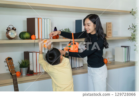 Halloween Decorating. A mother and son joyfully preparing Halloween decorations together. 129728066