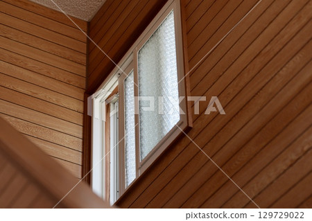 A small double-glazed window on the second floor of an old wooden house 129729022