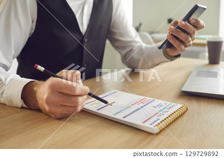 Business man planning daily appointment in planner schedule sitting in office. 129729892