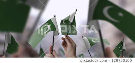Pakistan flags in their hands on a blurred urban background 129730100
