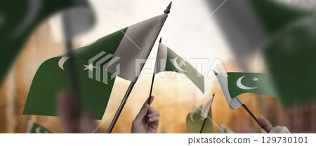 Pakistan flags in their hands on a blurred urban background 129730101