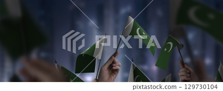 Pakistan flags in their hands on a blurred urban background 129730104