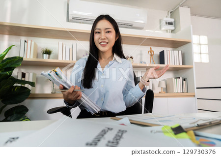 Professional Engagement. Smiling woman presenting ideas in a modern office setting. Professional Engagement. Smiling woman presenting ideas in a modern office setting. 129730376