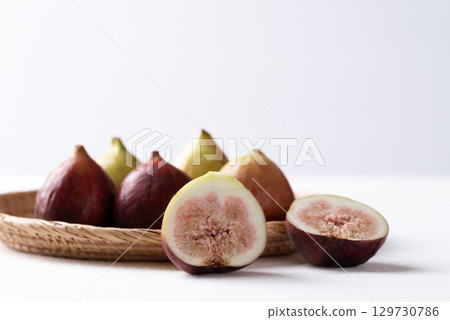 Fresh half fig and whole fruit in basket on white background, Autumn fruit 129730786