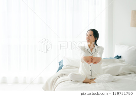 一位穿著睡衣的女士起身伸展身體 一位穿著睡衣的女士起身伸展身體 129731790