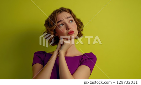 pensive young woman in purple dress against yellow background 129732011
