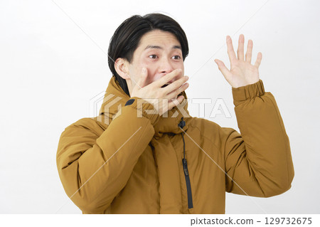A man wearing a down jacket is surprised on a white background A man wearing a down jacket is surprised on a white background 129732675