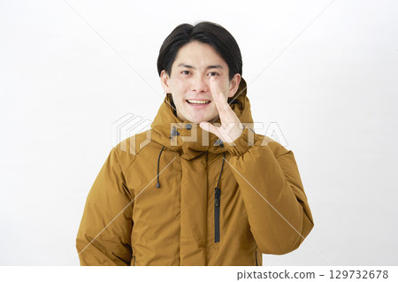 A man wearing a down jacket talking on a white background A man wearing a down jacket talking on a white background 129732678