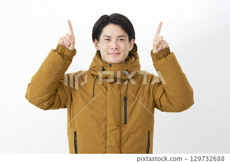 一位身穿羽絨外套的男子在白色背景上指著上方 129732688