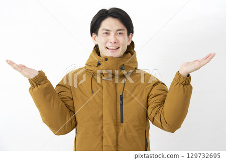 一名身穿羽絨外套的男子用手掌指向白色背景上的左右 129732695