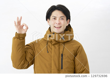 Man wearing down jacket OK sign white background 129732696