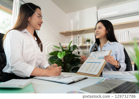 Strategic Discussion. Women presenting financial data in a collaborative office environment. 129732786