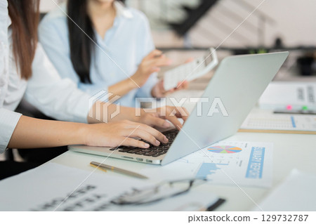 Digital Collaboration. Professional typing on a laptop while discussing with a colleague. 129732787