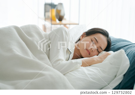 A young woman sleeping in bed 129732802