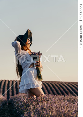 A Woman in a White Dress and Black Hat in a Lavender Field 129732823