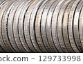 Reeded edges of silver coins, close-up, from above. Circulated silver bullion coins of one troy ounce of 99.9 percent pure silver each, also known as 999 fine silver, neatly arranged in a row. Photo 129733998