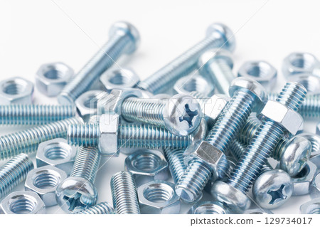 Pan head screws (cross recess) and nuts on a white background 129734017