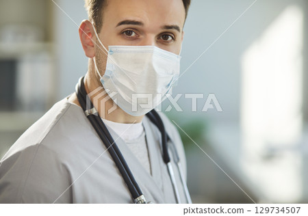 Physician, surgeon doctor, serious male nurse medical professional looking, wearing face mask Physician, surgeon doctor, serious male nurse medical professional looking, wearing face mask 129734507
