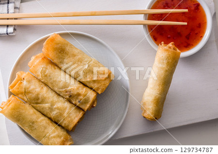 Fried spring rolls with sweet and saur sauce on white table. Top view. Fried spring rolls with sweet and saur sauce on white table. Top view. 129734787
