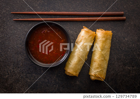 Fried spring rolls and sweet and sour sauce on wooden table. Top view. 129734789