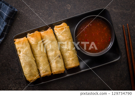 Fried spring rolls and sweet and sour sauce on wooden table. Top view. Fried spring rolls and sweet and sour sauce on wooden table. Top view. 129734790