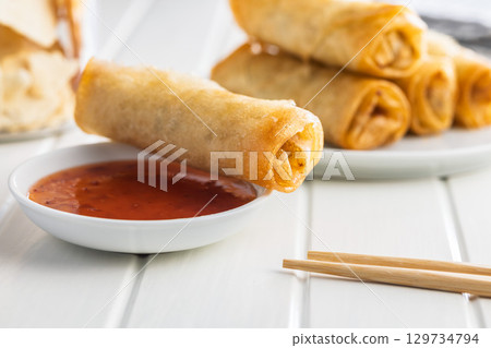 Fried spring rolls with sweet and saur sauce on white table. 129734794