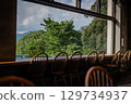 Tables and chairs. Greenery can be seen from the cafe window. 129734937