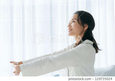 A woman in pajamas waking up in the morning and opening the window 129735024