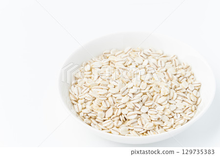 Rolled barley in a plate on a white background Rolled barley in a plate on a white background 129735383