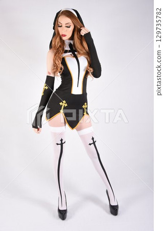 Tall, attractive, redhead model dressed as a fantasy Nun, isolated against a white background 129735782