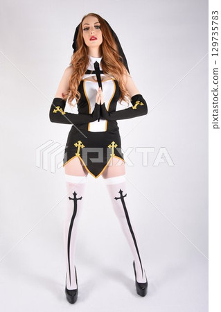 Tall, attractive, redhead model dressed as a fantasy Nun, isolated against a white background 129735783