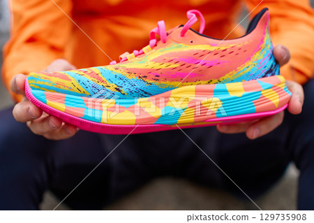 Close-up of colorful running shoe in hands 129735908