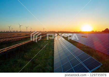 Solar panels and wind turbines at sunset. Renewable energy production 129735978